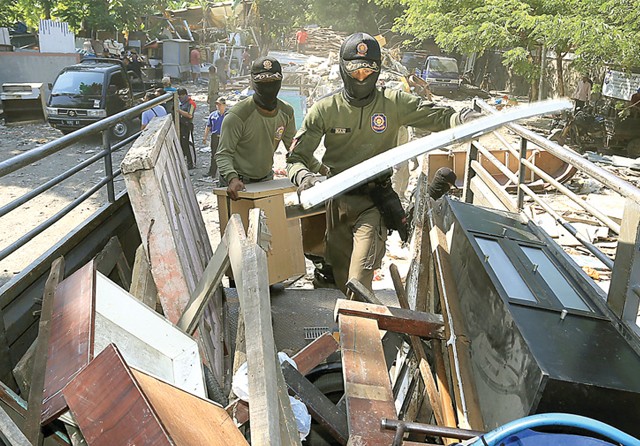 RAPIKAN DULU: Petugas gabungan mengangkut barang-barang rongsokan di lahan yang bakal menjadi akses penghubung Jalan Dharmahusada dan Jalan Ir Soekarno kemarin. (Robertus Risky/Jawa Pos) - Image