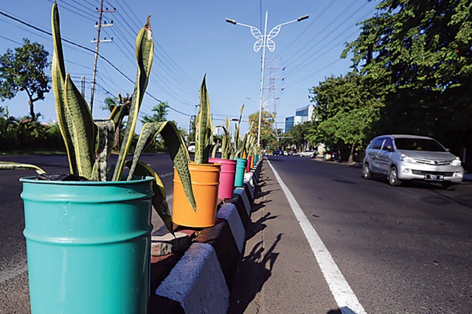 LEBIH TERTIB : DKRTH memasang pot bekas tempat cat di sepanjang Jalan Sukolilo Lor sehingga memperindah kawasan tersebut. (Robertus Risky/Jawa Pos) - Image