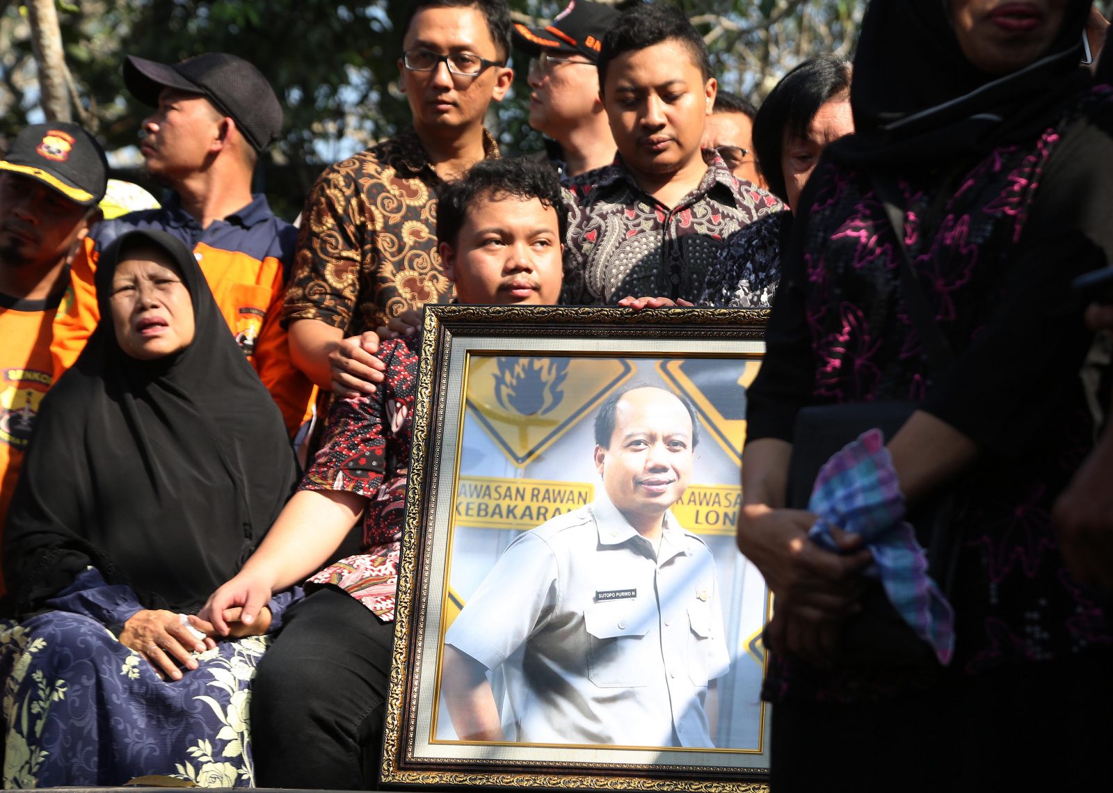 Kedua anak Sutopo Purwo Nugroho memegang bingkai foto almarhum pada saat pemakaman lalu. (Fedrik Tarigan/Jawa Pos) - Image