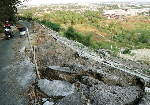 TANGANI YANG URGENT DULU: Kondisi Jalan Putri Cempo yang rusak berat karena pleng sengan penahan longsor rusak. Pengendara harus ekstrahati-hati saat melintas di sana. (Chusnul Cahyadi/Jawa Pos) - Image