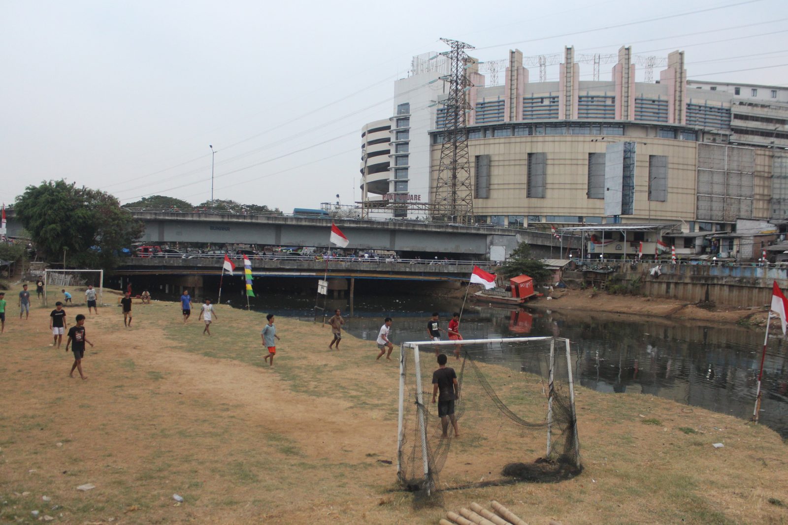 Sejumlah anak bermain bola di pinggir kali ciliwung Ciliwung, Roxy, Jakarta, Rabu (28/8/2019). Minimnya lahan bermain anak membuat mereka pinggiran kali Ciliwung yang kering untuk bermain bola. Foto: Dery Ridwansah/ JawaPos.com - Image