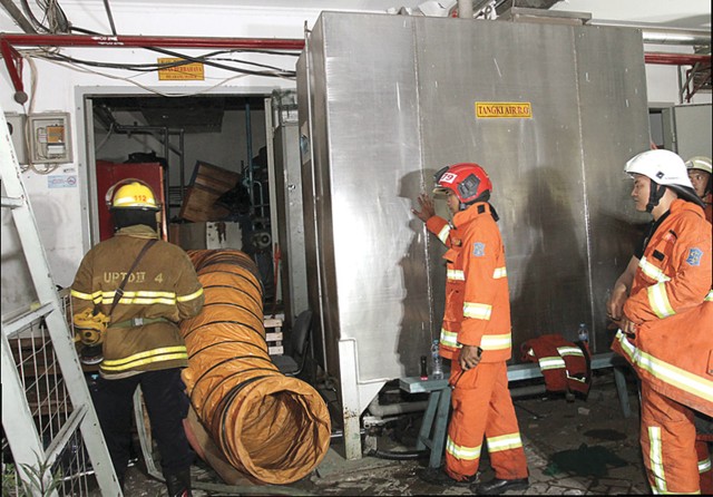 BERGERAK CEPAT: Petugas PMK berusaha memadamkan api pada genset di GBPT RSUD dr Soetomo kemarin (17/10). (Robertus Risky/Jawa Pos) - Image