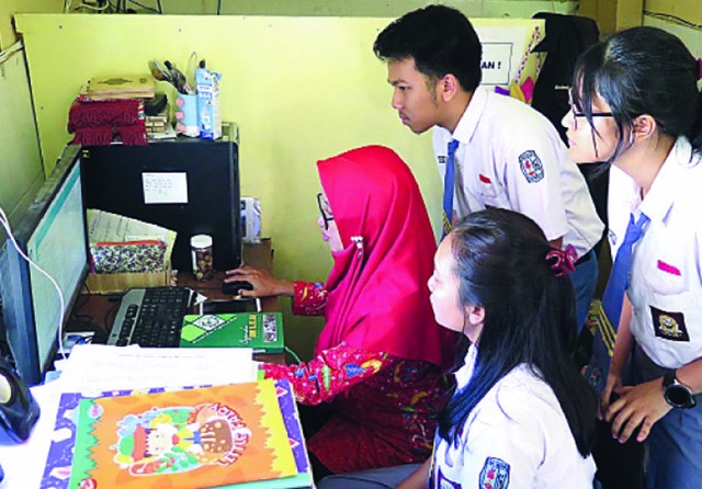 TUNTAS: Proktor utama SMAN 16 Maulandani Lisdiasari (kiri) mengecek data siswa sebelum dikirim ke website Kemendikbud kemarin. (Septinda Ayu/Jawa Pos) - Image