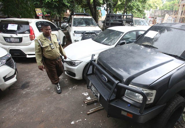 Petugas Kejaksaan berada di dekat aset First Travel berupa mobil yang terparkir di Halaman Kejaksaan Negeri Depok, Jawa Barat, Kamis (21/11/2019). Mahkamah Agung menyita ratusan barang bukti aset kasus First Travel yang ditempatkan di Kejaksaan Negeri Dep - Image