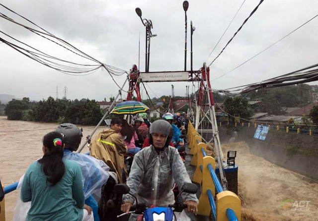 Sejumlah warga melintasi jembatan Bendung Katulampa, Kecamatan Sindangrasa Bogor Timur, Kota Bogor, Rabu (1/1) pagi. Saat ini Bendung Katulampa berstatus siaga 2 dengan debit 340 meter kubik per detik. (ACTNews fo JawaPos.com) - Image
