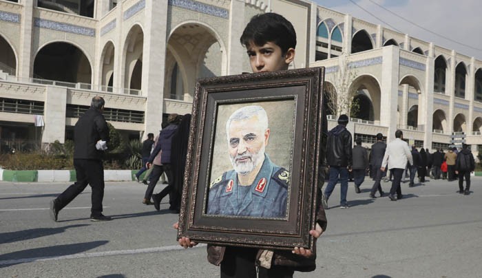 DUKA MENDALAM: Seorang bocah membawa potret Qasem Soleimani di Teheran, Iran. Soleimani tewas akibat serangan lewat drone MQ-9 Reaper milik AS. (Vahid Salemi/AP) - Image