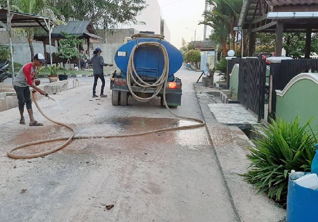 Pekerja tengah membersihkan material di jalan akibat material yang terbawa saat saluran meluap di Perumahan Citra Batam. (Istimewa) - Image
