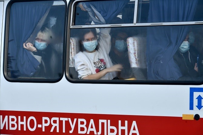 Evacuees from coronavirus-hit China look out from a bus as they leave an airport in Kharkiv on February 20, 2020. - On Thursday a plane carrying 45 Ukrainians and 27 foreign nationals from the Chinese city of Wuhan, the epicentre of the deadly coronavirus - Image