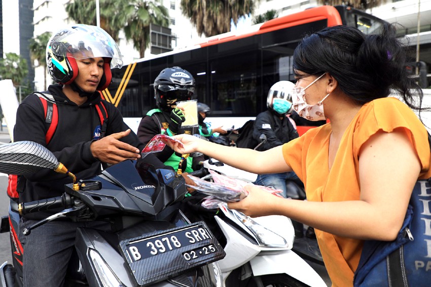 Warga membagikan masker di pelican crossing Halte Bundaran HI, Jakarta, Sabtu (21/3/2020). Kegiatan tersebut merupakan bentuk empati warga untuk mencegah penyebaran Covid-19 yang hingga saat ini telah merenggut puluhan nyawa. FOTO: SALMAN TOYIBI/ JAWA POS - Image