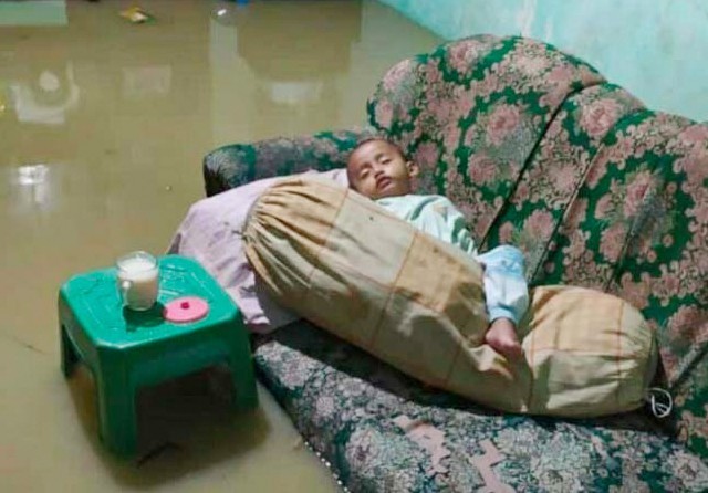 bayi tertidur pulas di sebuah rumah yang tergenang air di RT 04 Desa Tanjungan, Driyorejo. (Istimewa0 - Image