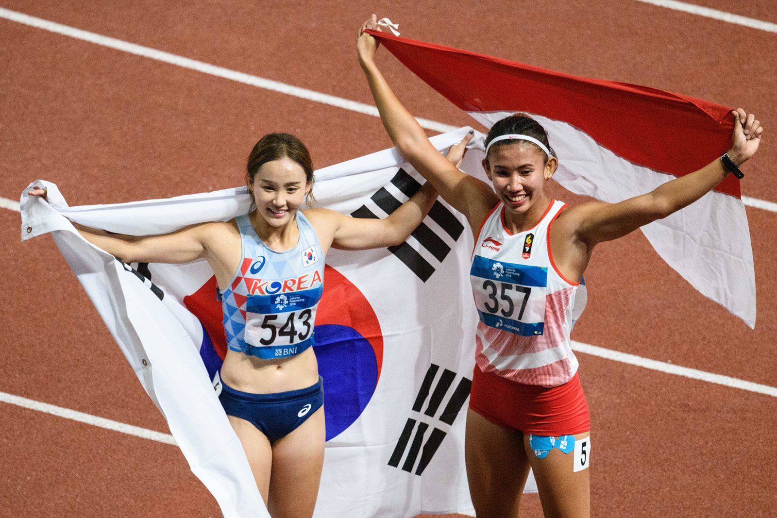 Emilia Nova dan atlet Korea Selatan Jun Hye-lim 100 meter lari gawang Asian Games 2018. (Anthony Wallace/AFP) - Image