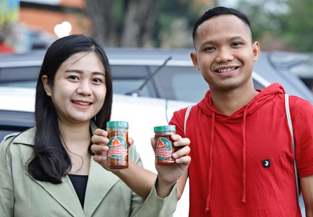 Oktafianus Fernando (kanan), winger Persebaya bersama sang istri Gabriella Hocky Fitria Loexyanta, membawa Sambel Mama Hocky hasil produksi mereka berdua saat ditemui di Gedangan, Sidoarjo, kemarin (19/5). FOTO: Angger Bondan/Jawa Pos - Image