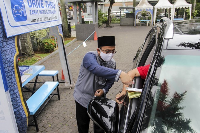 Petugas Amil Zakat menerima pembayaran Zakat melalui sistem Drive Thru dari kendaraan dari warga yang menyalurkan zakat di halaman Masjid Nurul Hidayah, Tanah Kusir, Jakarta, Jumat, (22/5/2020). Layanan penerimaan (pembayaran) zakat dengan sistem Drive T - Image