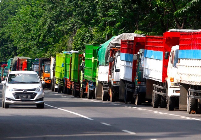 MENGANTRE: Truk menunggu kedatangan kapal di Pelabuhan Tanjung Perak kemarin (5/5). Saat ini banyak angkutan barang yang tidak beroperasi karena terdampak pandemi. (Ahmad Khusaini/Jawa Pos) - Image