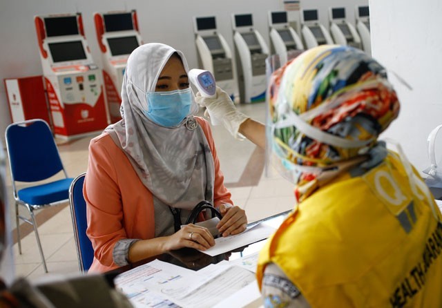 PEMERIKSAAN KETAT: Petugas KKP Kelas I Surabaya mengecek suhu tubuh calon penumpang yang berangkat dari Bandara Internasional Juanda. (Dipta Wahyu/Jawa Pos) - Image