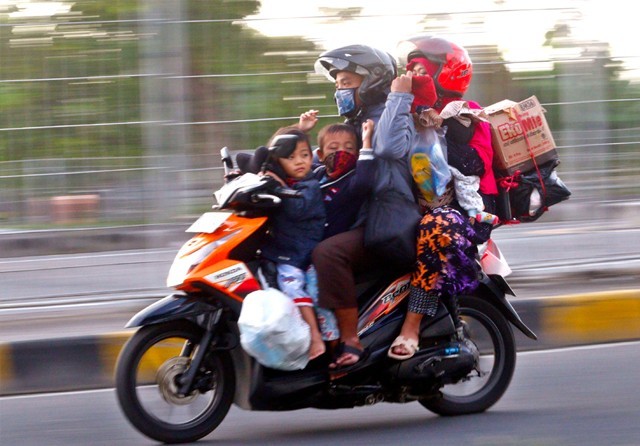 ABAIKAN PROTOKOL KESEHATAN: Pengendara sepeda motor yang melintas di Suramadu memboncengkan anak dan istrinya. (Ahmad Khusaini/Jawa Pos) - Image