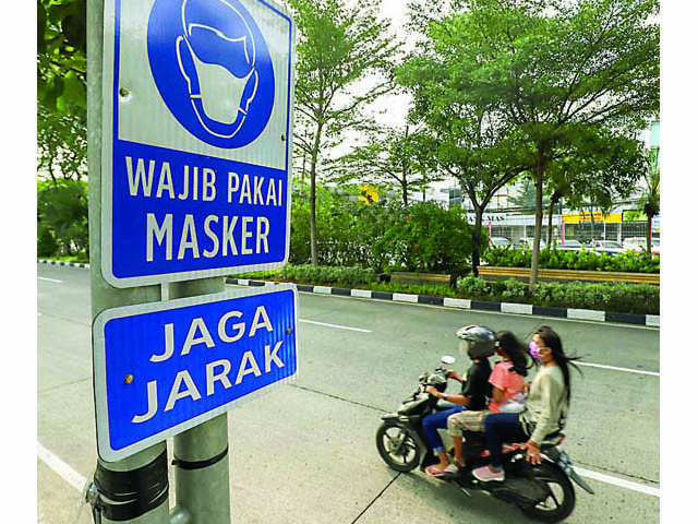 INGATKAN WARGA: Rambu wajib memakai masker dan menjaga jarak dipasang di Jalan Mayjen Sungkono, Surabaya, kemarin. (Allex Qomarulla/Jawa Pos) - Image