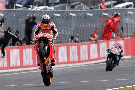 Japanese Grand Prix winner Repsol Honda Team rider Marc Marquez of Spain (L) pops a wheelie to cross the finish line ahead of second placed Petronas Yamaha SRT rider Fabio Quartararo of France (R) during the MotoGP class Japanese Motorcyle Grand Prix at t - Image