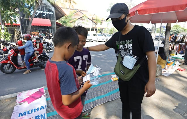 Bonek Green Nord membagikan masker di kawasan Masjid Al Akbar, Surabaya, kemarin (19/7). FOTO: Angger Bondan/Jawa Pos - Image