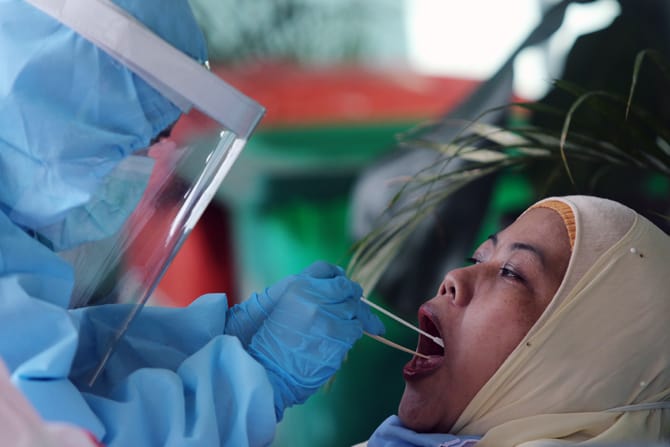 Petugas medis melakukan pengambilan cairan di tenggorokan dan hidung warga saat Swab test PCR Covid-19 di Jakarta. Foto: Dery Ridwansah/ JawaPos.com - Image