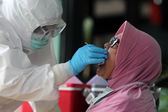Petugas medis melakukan pengambilan cairan di tenggorokan dan hidung warga saat Swab test PCR Covid-19 di Jakarta. Foto: Dery Ridwansah/ JawaPos.com - Image