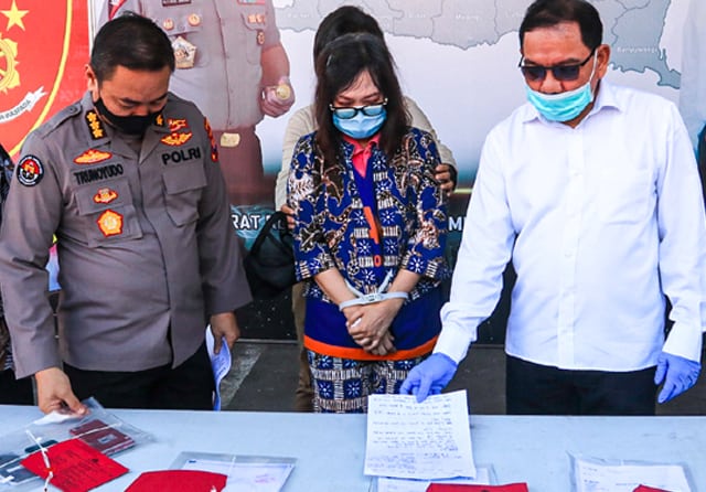DALAM PENYIDIKAN: Tersangka Devy Chrisnawati diapit Dirreskrimum Polda Jatim Kombespol Pitra Andreas Ratulangie (kanan) dan Kabidhumas Polda Jatim Kombespol Trunoyudo Wisnu Andiko di Mapolda Jatim (23/7). (Dimas Maulana/Jawa Pos) - Image