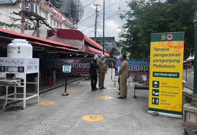 Petugas Jogoboro menjaga akses masuk Malioboro untuk memastikan wisatawan memindai QR Code dan pengecekan suhu tubuh. Eka A.R./Antara - Image