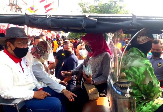 Menkopolhukam Mahfud M.D. menaiki andong bersama istri Zaizatun Nihayati setelah bagi-bagi masker di kawasan Malioboro, Jogjakarta, Minggu (30/8). Luqman Hakim/Antara - Image