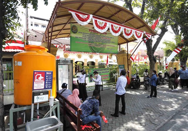 TIDAK BOLEH MASUK: Petugas Pengadilan Negeri Surabaya berjaga di depan gerbang. Mereka menolak siapa pun yang akan memohon layanan pengadilan. (Guslan Gumilang/Jawa Pos) - Image