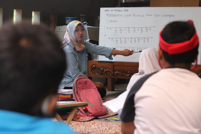 Guru saat memberikan materi kepada murid di garasi teras yang dijadikan kelas di Pondok Labu, Tangerang Selatan, Jakarta (10/8/2020). Kegiatan ini terpaksa dilakukan karena murid mengalami kesulitan menguasai materi pelajaran saat proses belajar secara on - Image