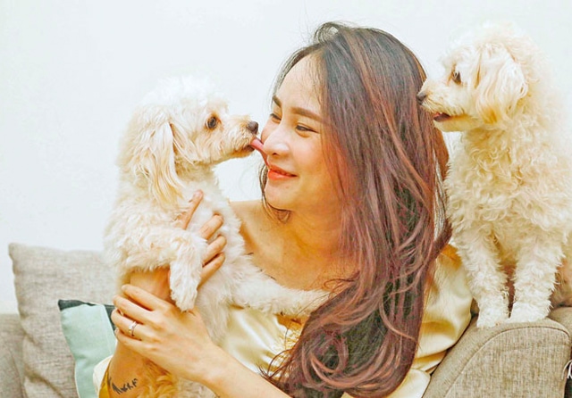 KASIH IBU: Imel diapit dua Toy Poodle miliknya. Dia menganggap delapan anjingnya seperti anak sendiri. (Puguh Sujiatmiko/Jawa Pos) - Image