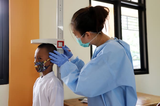 Seorang siswa dicek kondisi berat badan dan tinggi tubuh oleh petugas kesehatan sebelum imunisasi di balai warga Pademangan Timur, Jakarta Utara, Jumat (23/10/2020). Bulan Imunisasi Anak Sekolah (BIAS) berlangsung pada 21 Oktober hingga 9 November mendata - Image