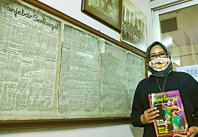 BERDEDIKASI: Pemimpin Redaksi Majalah Panjebar Semangat Arkandi Sari berdiri di samping cetakan pertama majalah berbahasa Jawa itu yang terbit 2 September 1933. Foto kanan, Berlianik sedang menjilid Panjebar Semangat yang akan dikirim kepada pelanggan. (M - Image