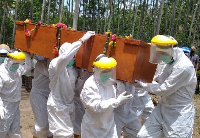 Petugas membawa jenazah pasien yang dimakamkan secara protokol Covid-19 di Kabupaten Jember. PMI Jember/Antara - Image