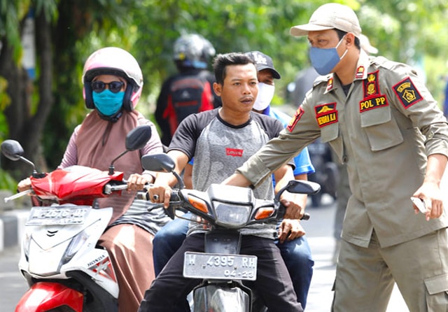 TIDAK BERI KESEMPATAN KABUR: Anggota Satpol PP Hendra K. (kanan) menghentikan pengguna jalan yang tidak memakai masker. Samsul Huda (tengah), saat operasi yustisi penegakan hukum protokol kesehatan di depan kantor Kecamatan Sedati, Sidoarjo, Kamis (11/11) - Image