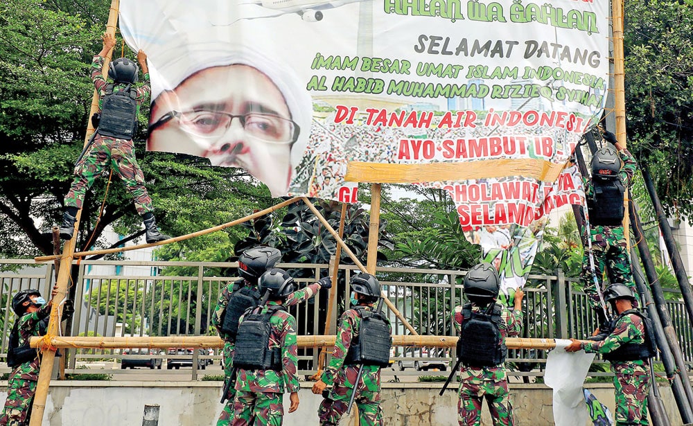 PENERTIBAN: Prajurit TNI mencopot baliho bergambar Rizieq Syihab di kawasan Petamburan, Jakarta Pusat, kemarin (20/11). (FEDRIK TARIGAN/JAWA POS) - Image
