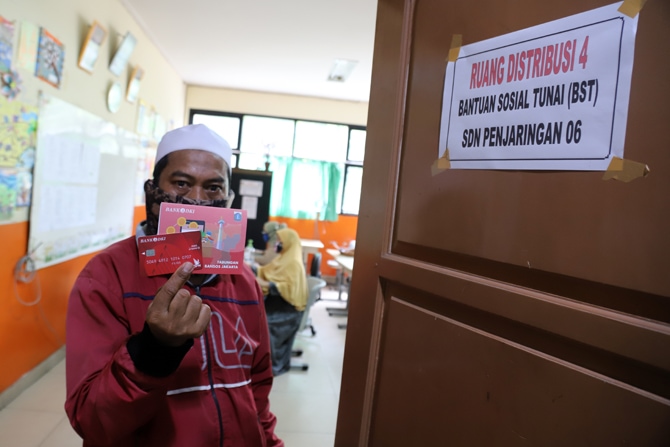 Warga saat mengantre untuk menerima Bantuan Sosial Tunai (BST) keluarga penerima manfaat di SDN Penjaringan 06, Jakarta Utara, Selasa (19/1/2021). Pemerintah menyalurkan BST untuk empat bulan kedepan sebesar Rp 300.000 per keluarga penerima manfaat yang - Image