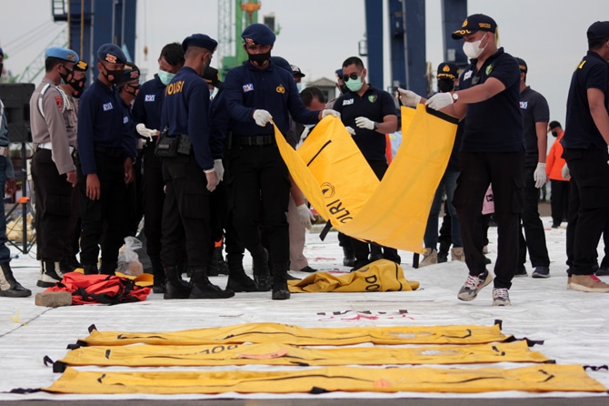 Petugas memeriksa kantung jenazah berisi potongan tubuh korban pesawat Sriwijaya Air PK-CLC yang jatuh di perairan Pulau Seribu di Dermaga JICT, Jakarta, Senin (11/1/2021). Temuan tersebut kemudian dibawa ke RS Polri untuk di identifikasi. Foto: Dery Ridw - Image