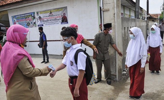 Seorang guru mengukur suhu tubuh siswa yang akan masuk ke sekolah mengikuti simulasi pembelajaran tatap muka di SDN Karang Raharja 02, Cikarang, Kabupaten Bekasi, Jawa Barat, beberapa waktu lalu. Fakhri Hermansyah/Antara - Image
