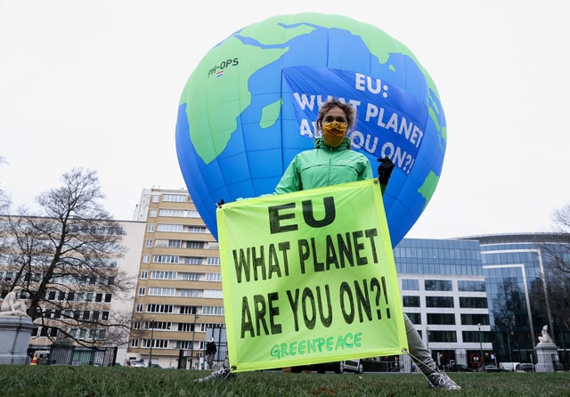 SINDIRAN: Seorang aktivis Greenpeace memegang spanduk - Image