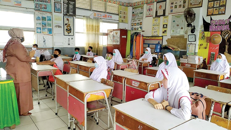 JAGA JARAK: Pembelajaran tatap muka untuk kali pertama di SDN 06 Kp Lapai, Kota Padang, Sumbar, Senin (4/1). RANDI ZULFAHLI/PADANG EKSPRES - Image