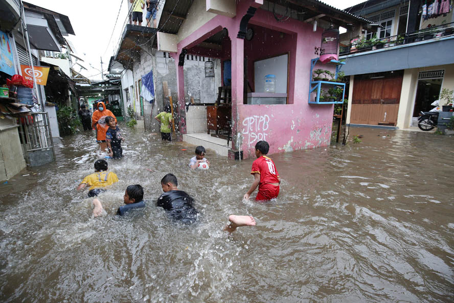Anak-anak bermain saat banjir di kawasan Tebet Barat, Jakrta, Kamis (18/2/2020).Banjir tersebut dikarenakan intensitas hujan yang tinggi.FOTO:MIFTAHULHAYAT/JAWA POS - Image
