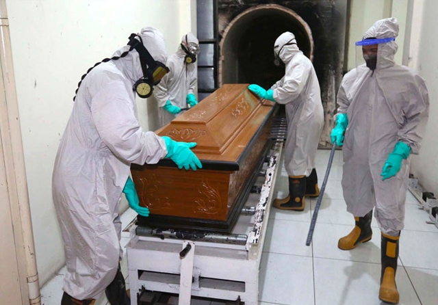 GUNAKAN APD LENGKAP: Petugas krematorium TPU Keputih bersiap-siap melakukan pembakaran jenazah pasien Covid-19 yang butuh waktu sekitar 1,5 jam. (Robertus Risky/Jawa Pos) - Image