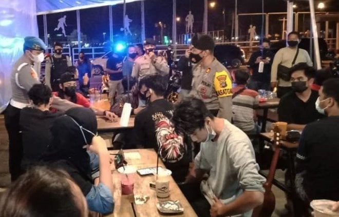 Anggota polisi mendatangi sebuah kafe dipenuhi anak muda dalam razia protokol kesehatan. Polres Banjarbaru/Antara - Image