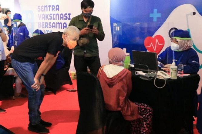 Gubernur Jawa Tengah Ganjar Pranowo berbincang dengan seorang lansia penerima vaksin Covid-19 di sentra vaksinasi di Kawasan PRPP, Kota Semarang, Minggu (21/3). Humas Pemprov Jateng/Antara - Image