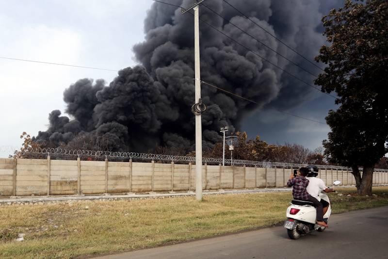Warga melintas di depan lokasi kebakaran tangki minyak milik Pertamina RU VI Balongan, Indramayu, Jawa Barat, Selasa (30/3/2021). Hingga hari kedua titik api kebakaran tangki minyak balongan belum juga padam. FOTO: SALMAN TOYIBI/JAWA POS - Image