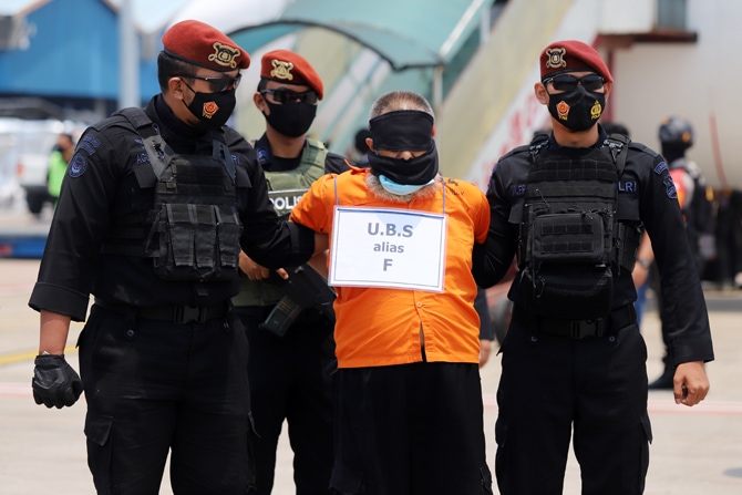 Personel Densus 88 Anti Teror membawa terduga teroris menuju mobil tahanan setibanya di Bandara Internasional Soekarno Hatta, Tangerang, Banten, Kamis (18/3/2021). Sebanyak 22 tahanan kasus terorisme jaringan Jamaah Islamiyah (JI) dari Jawa Timur tiba di - Image