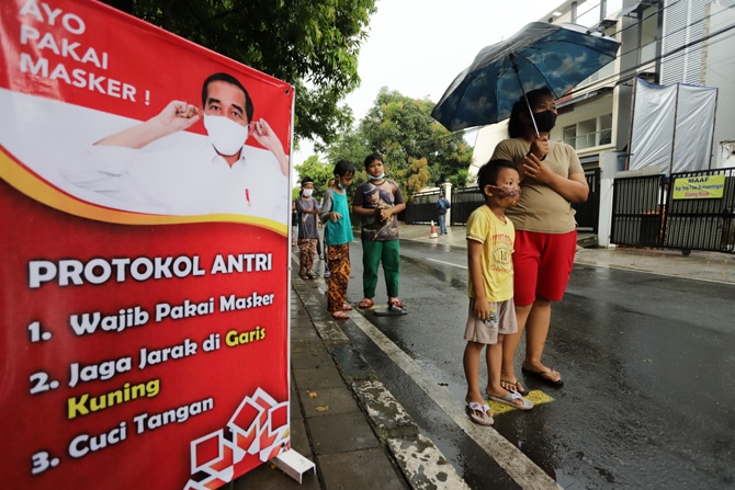 Sejumlah warga mengantre untuk mendapatkan takjil gratis di Jalan Cempaka Putih Tengah, Kecamatan Cempaka Putih, Jakarta, Rabu (14/04). Dalam rangka menerapkan aturan jarak fisik atau - Image