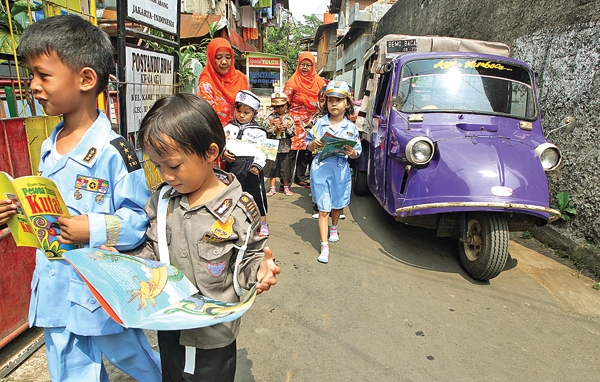 BEMO DAN BUKU: Ibu Wirda (kanan) guru sekaligus Kepala Sekoolah BKB PAUD Tumbuh Kembang Karet Tengsein, Jakarta Pusat, membimbing anak didiknya dan dan membaca buku di Bemo Baca Pak Kinong. (MUHAMAD ALI/JAWA POS)