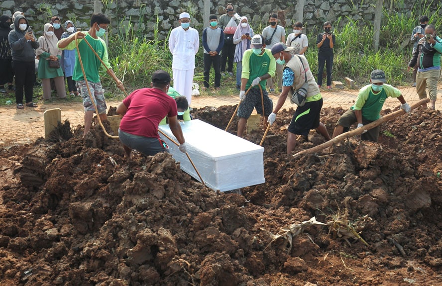 Petugas menurunkan jenazah ke liang lahat di area Covid-19 TPU Jombang Tangerang Selatan Banten, Jumat (13 Mei 2021). Mulai Maret 2020 hingga Hari Idul Fitri hari kedua Jumat 14 Mei 2021, sebanyak 825 jenazah dimakamkan secara Protol Kesehatan Covid-19 di - Image